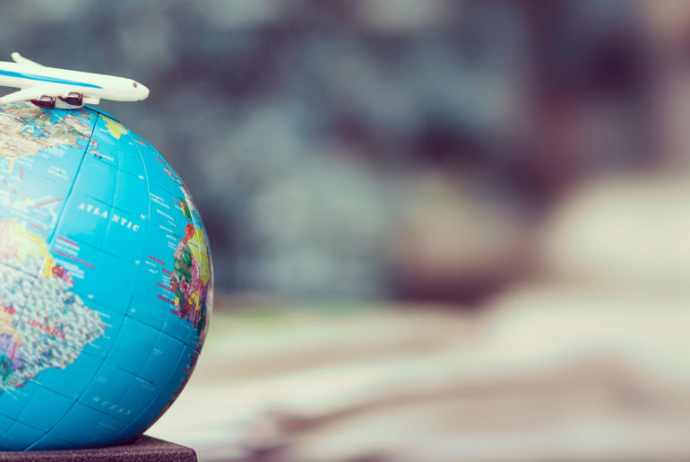 a toy airplane is sitting on top of a globe.