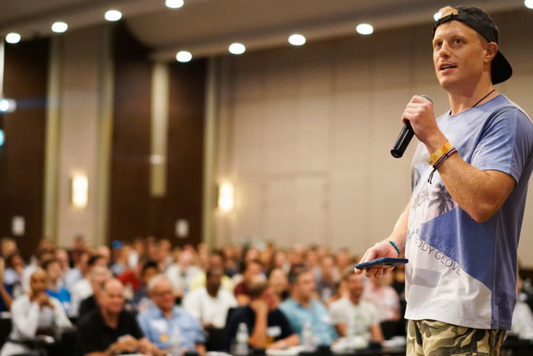 A man holding a microphone in front of a crowd at an event.
