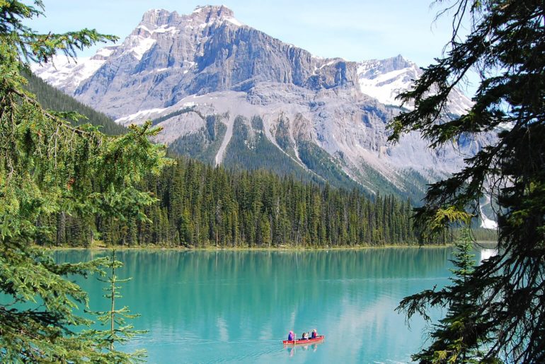 A person in a boat on a lake with mountain perspectives in the background.