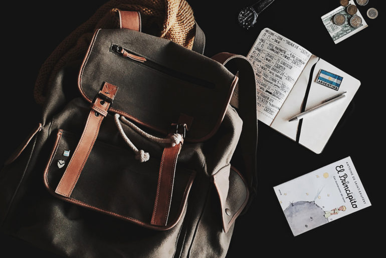 A travel essential brown backpack sitting on top of a table.