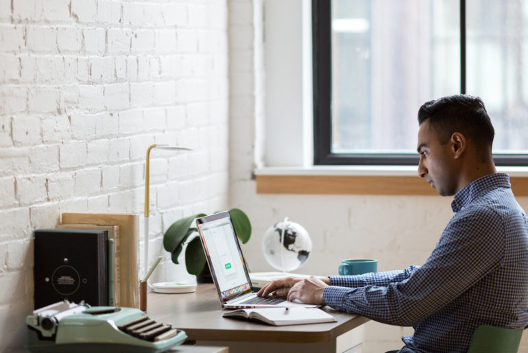 a man sitting at a desk working on a laptop.