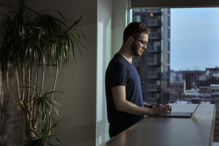 a man in a blue shirt is using a laptop.