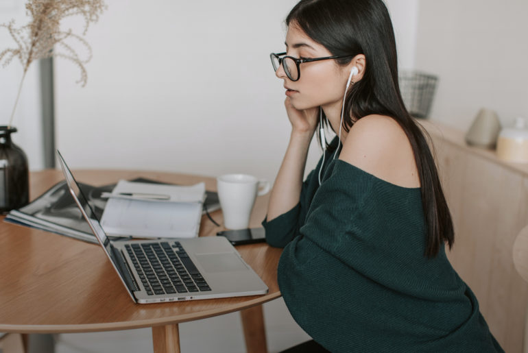 a woman sitting at a table with a laptop.
