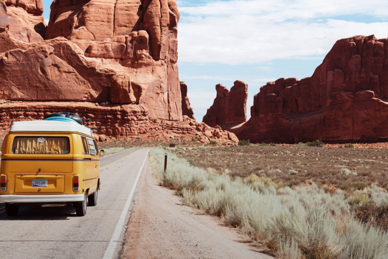 A nomad driving a yellow van down a desert road.