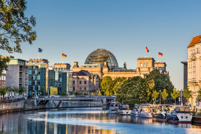 A river running through Berlin next to tall buildings, making it an ideal location for digital nomads.
