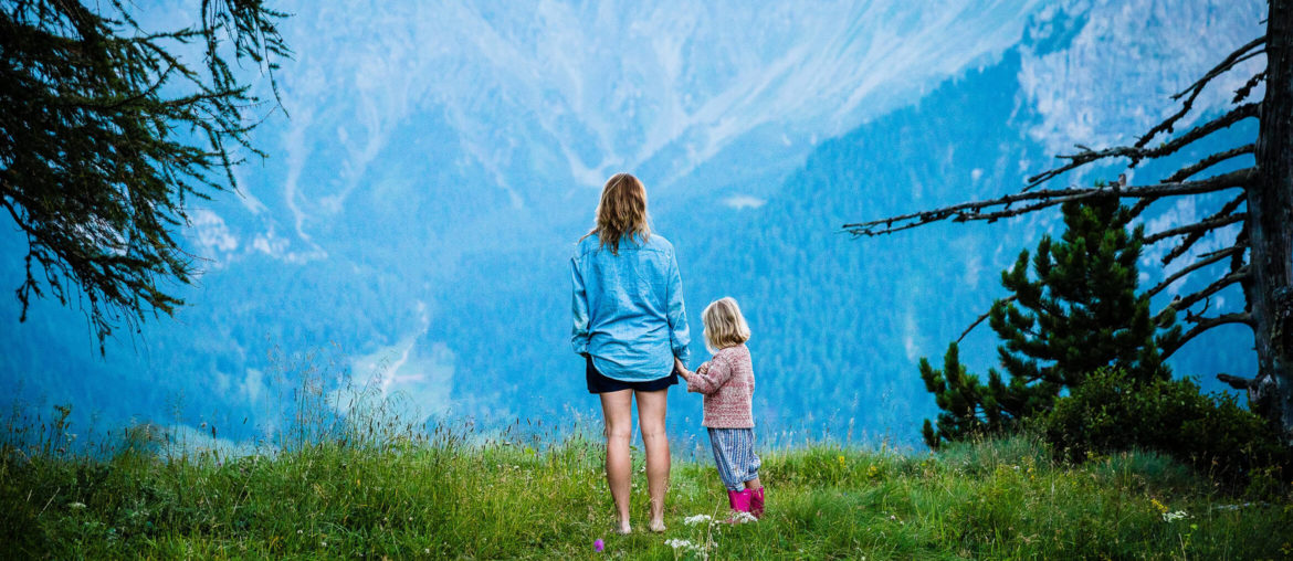 A digital nomad family standing on top of a lush green hillside.