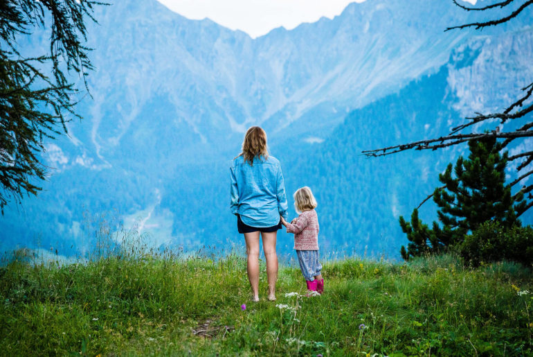 A digital nomad family standing on top of a lush green hillside.