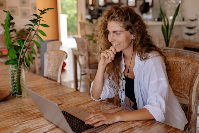 a woman sitting at a table using a laptop computer.