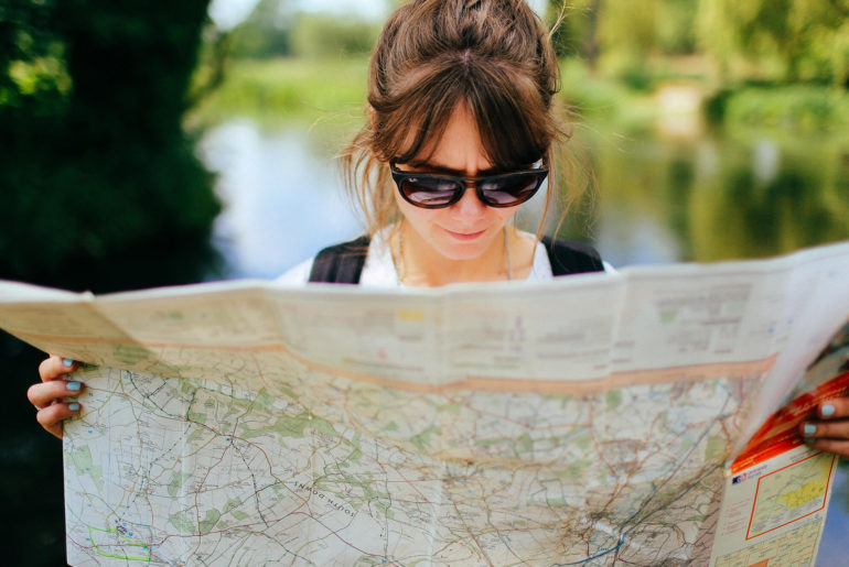 a woman in sunglasses looking at a map.