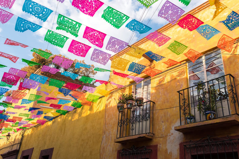 a building with a lot of colorful flags hanging from it's roof.