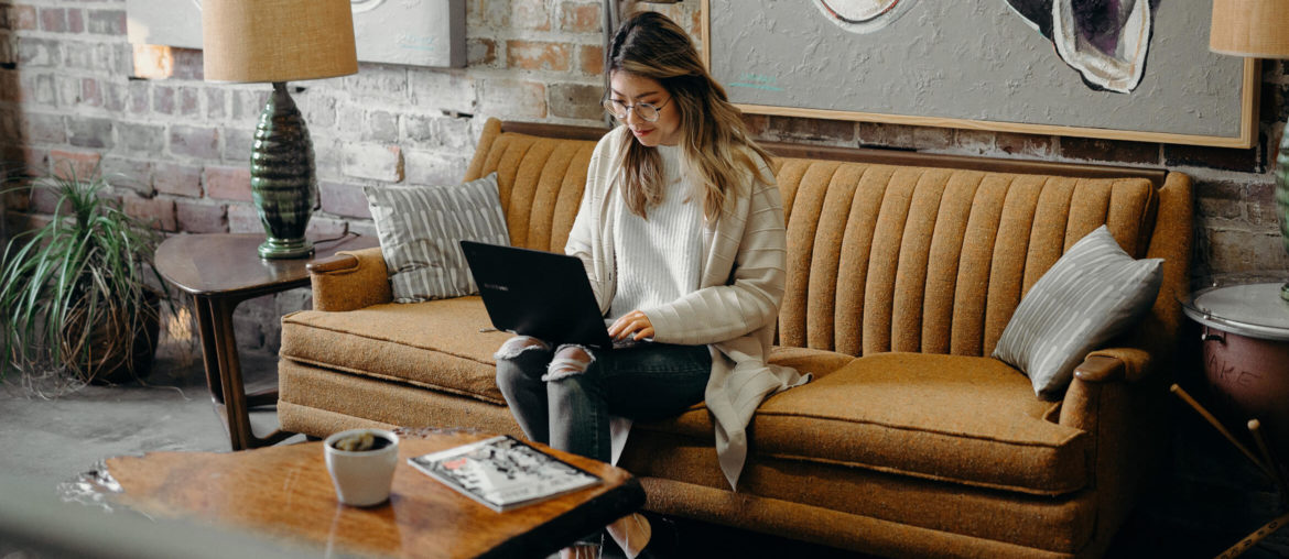 a woman sitting on a couch using a laptop.