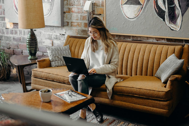 a woman sitting on a couch using a laptop.