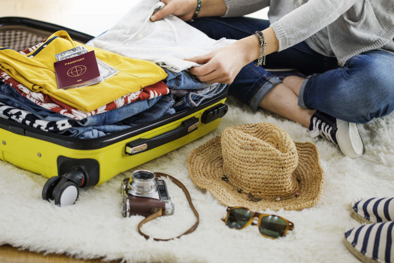 a woman packing her suitcase on a rug.