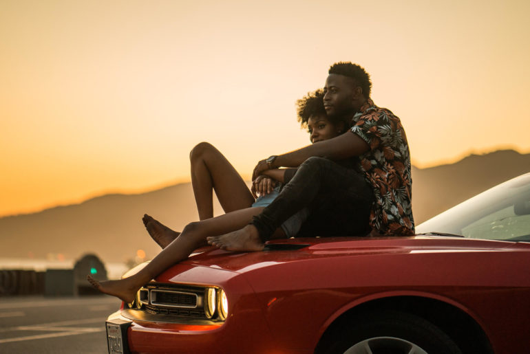 woman and man watching the sunset on the car