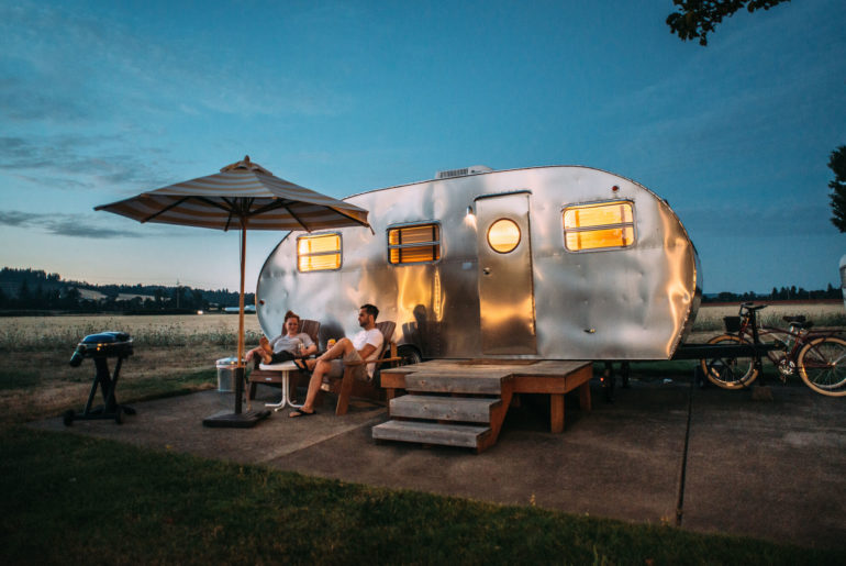 Two individuals living outside of a trailer.