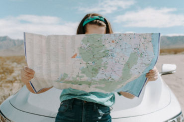 a woman holding a map in front of a car.