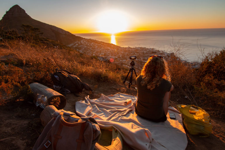 A woman enjoying the best workation destination on top of a hill with her bag.