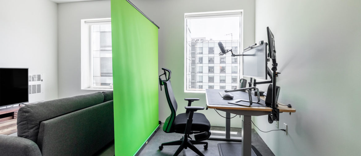 A rental living room with a green screen in the corner for remote work.
