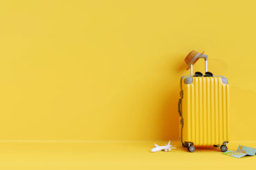 A minimalist yellow suitcase on a yellow floor.