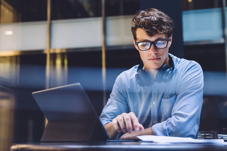 a man sitting at a table using a laptop computer.