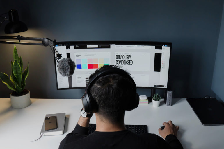 A man working remotely sits at his desk wearing headphones to improve productivity.