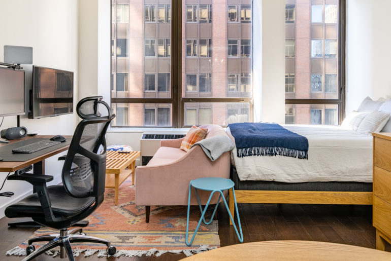 A relocated bedroom with a bed, desk, chair, and television.