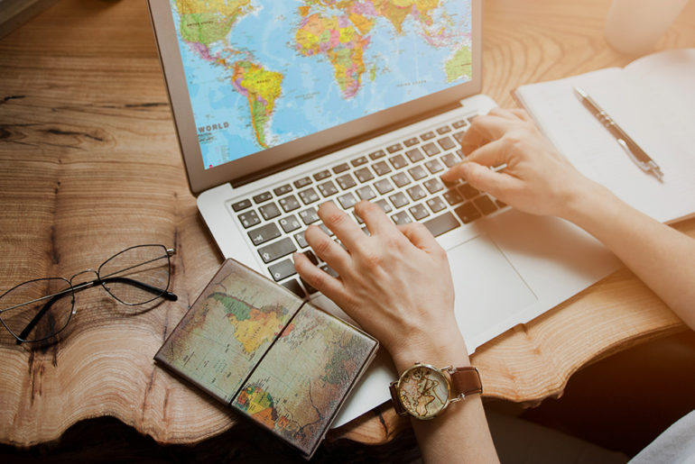 A woman working from anywhere using a laptop computer with a world map on the screen.