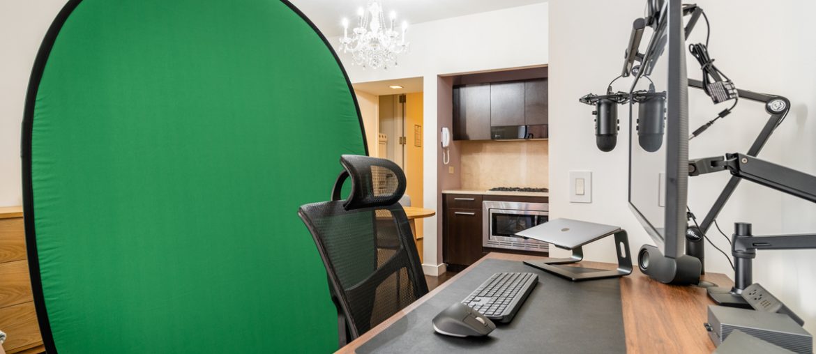 An office with a large green screen in the corner.