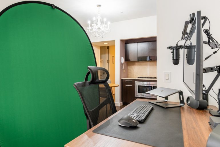 An office with a large green screen in the corner.