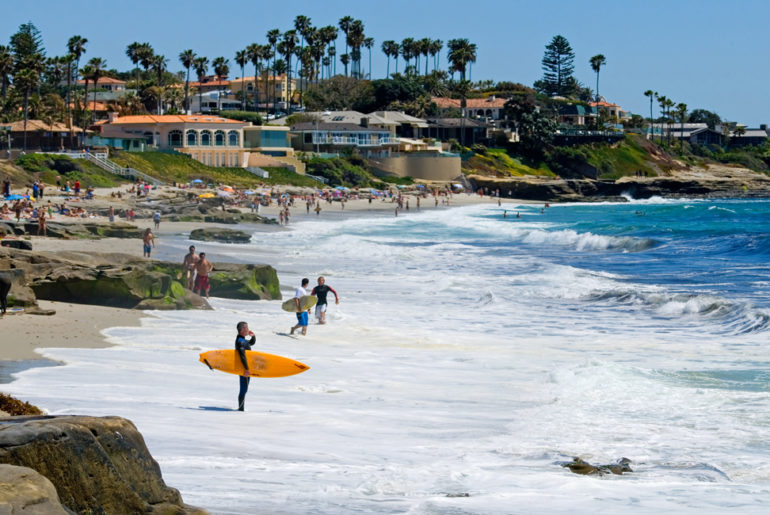 A workation group walking along a beach next to the ocean.