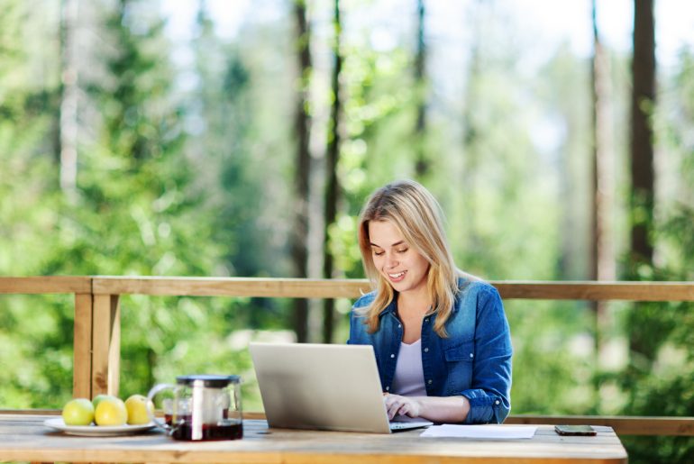 A woman working remotely on a laptop at a table.