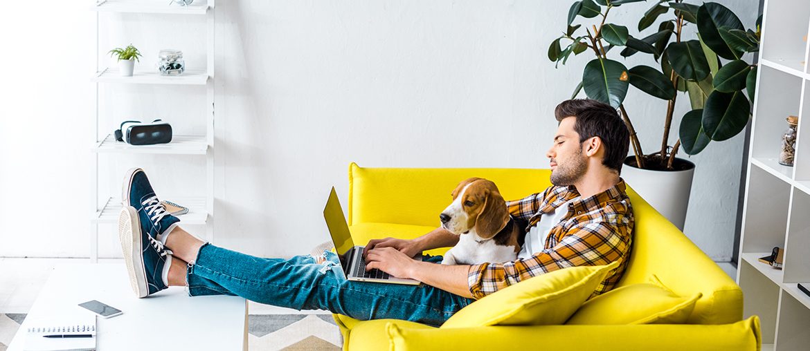A man on a yellow couch enjoying the benefits of pet ownership with his dog on his lap.
