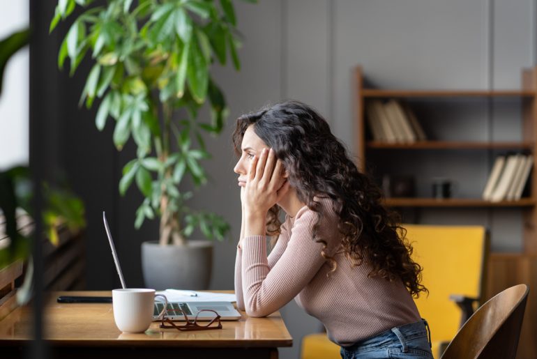 a woman sitting at a table with a laptop.
