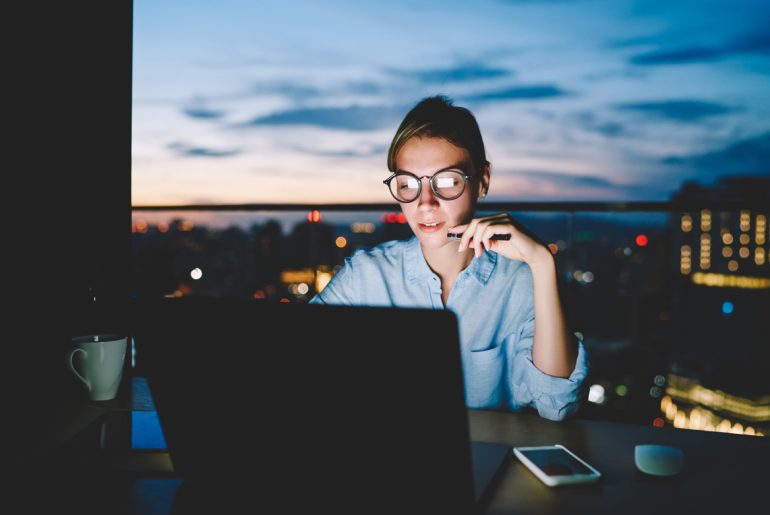 A woman working remotely at a table with a laptop.