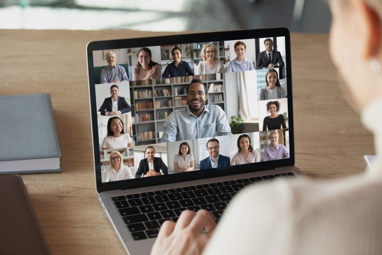 a woman is looking at a laptop screen with a group of people on it.