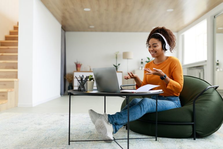 a woman sitting on a bean bag chair using a laptop.