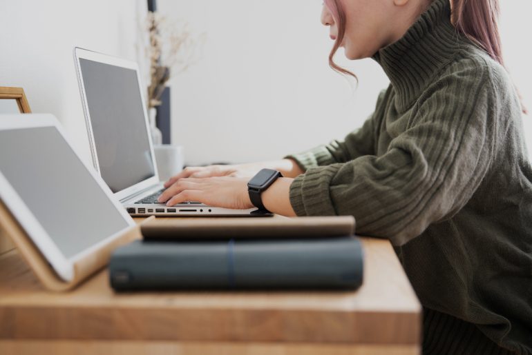 A woman performing remote work at her desk using a laptop computer.