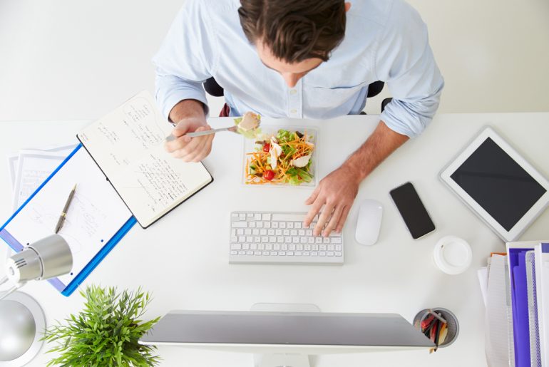 a man sitting at a desk with a laptop and a keyboard.