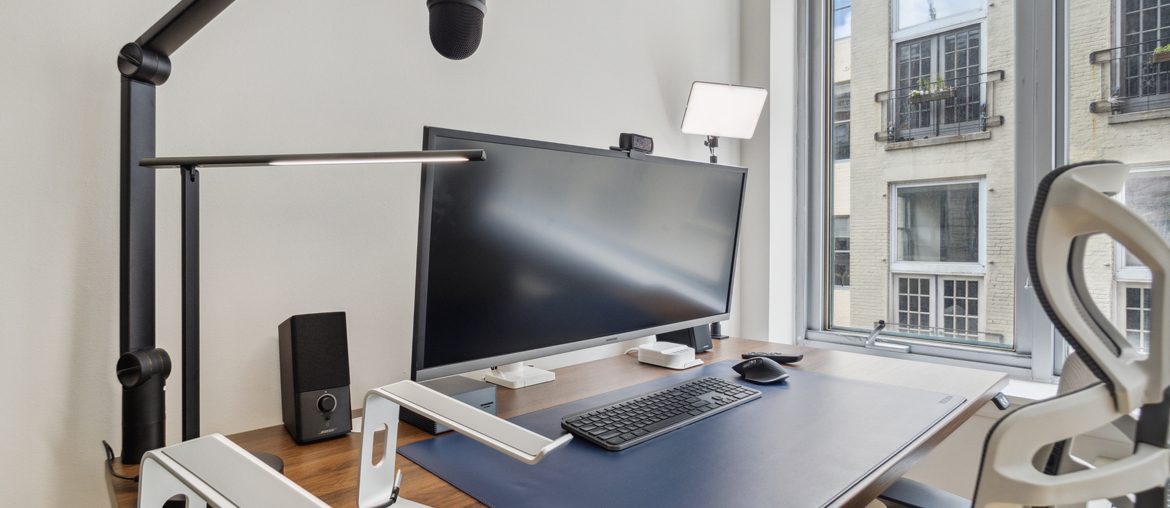 A workspace with a computer monitor, keyboard and mouse on a desk.