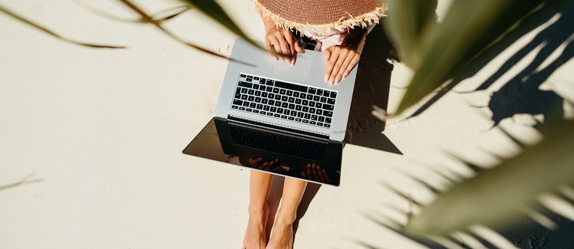 A remote worker wearing a floppy hat typing on her laptop.