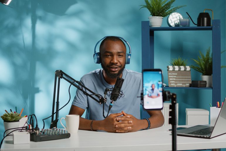 A creator sitting at a desk with headphones on.