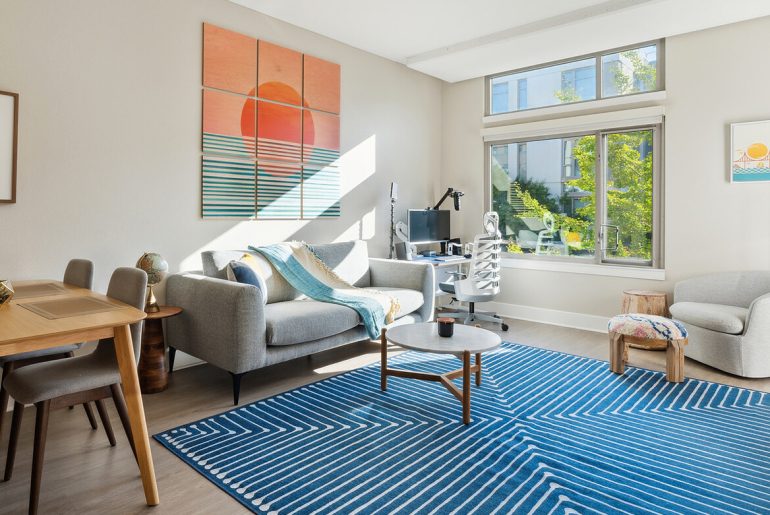 a flexible living room with a blue rug and various furniture pieces.