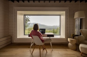 A woman on a workation sitting at a desk in front of a window.