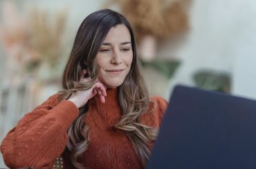 A remote employee sitting at a table, looking at her laptop.
