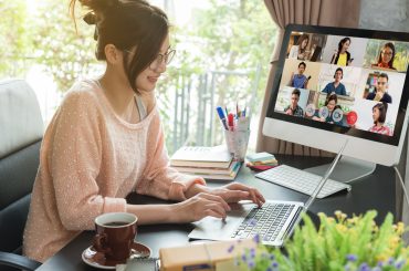 a woman is using a computer for a video call across different time zones.