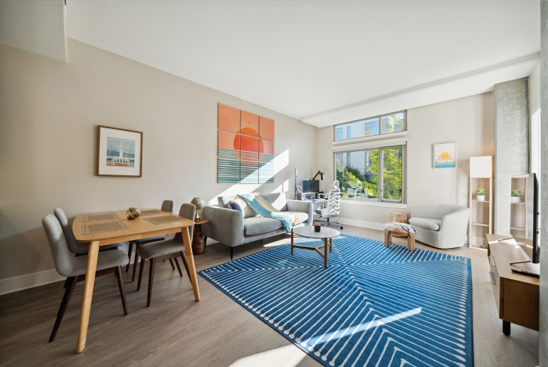 A relocated living room featuring a blue rug and hardwood floors.
