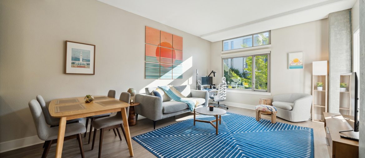 A flexible living room with a blue rug on hardwood floors.