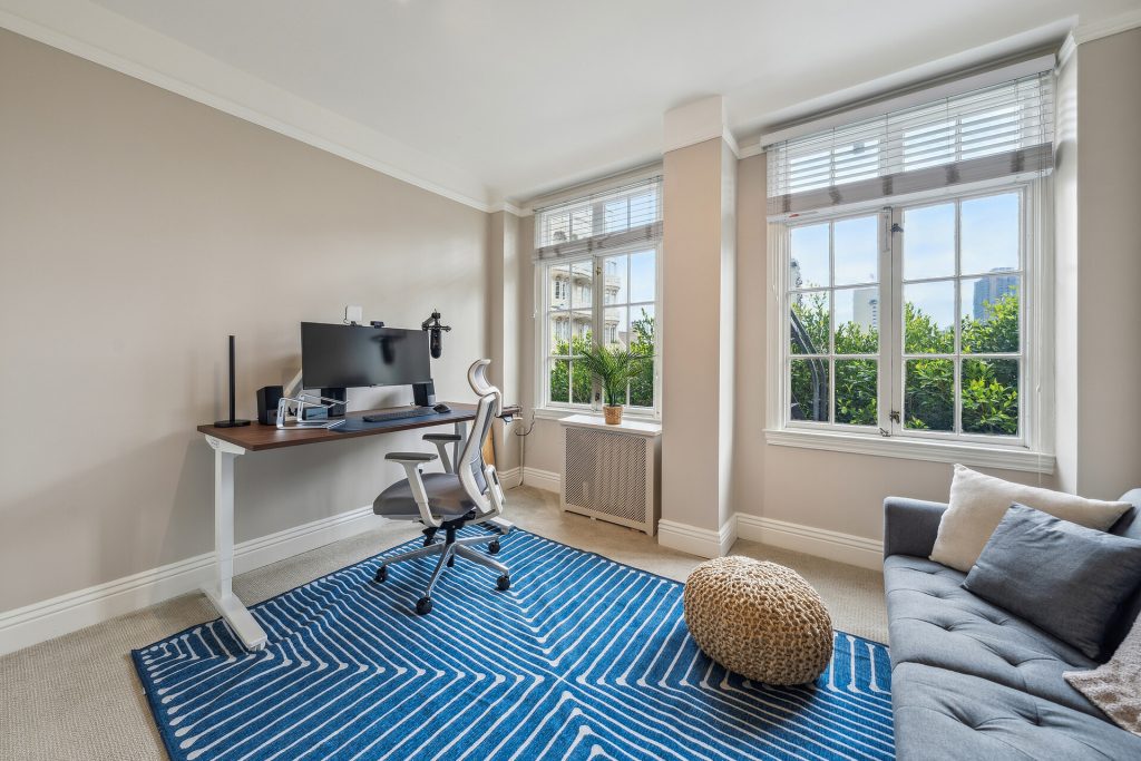 Bright home office with a modern desk setup, ergonomic chair, and a view of San Francisco greenery outside the window.